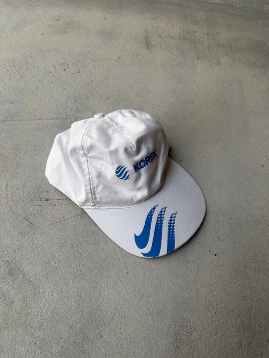 Vintage Korek cap in white with blue logo embroidery and curved brim.