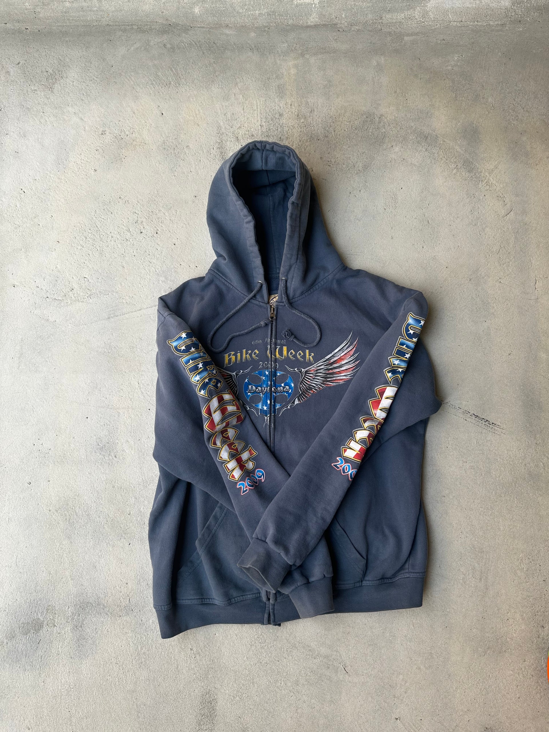 Laid-flat black zip-up hoodie with sleeve prints and worn-in details