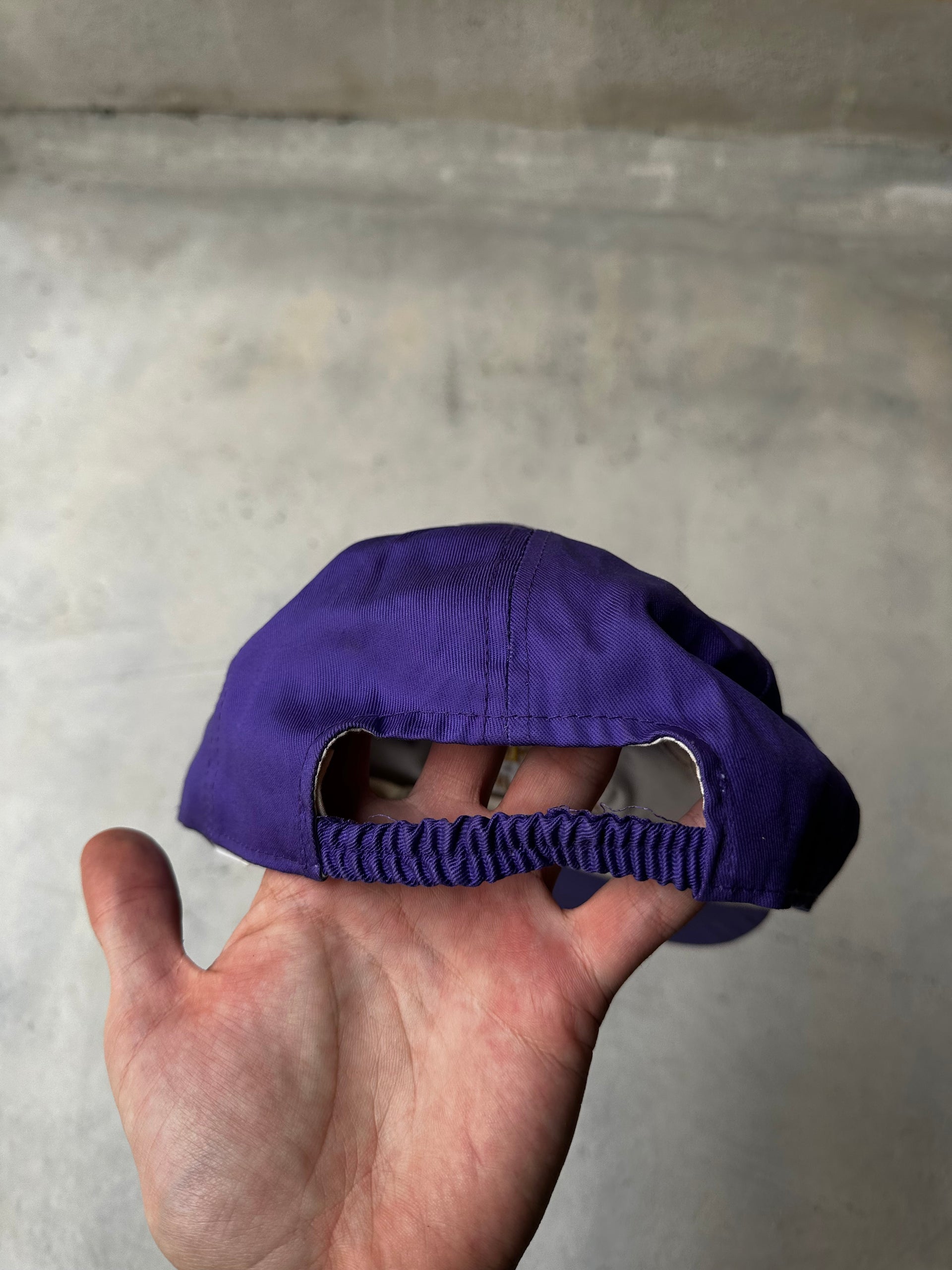 Hand holding vintage Blend Sun Equipment cap against neutral background.