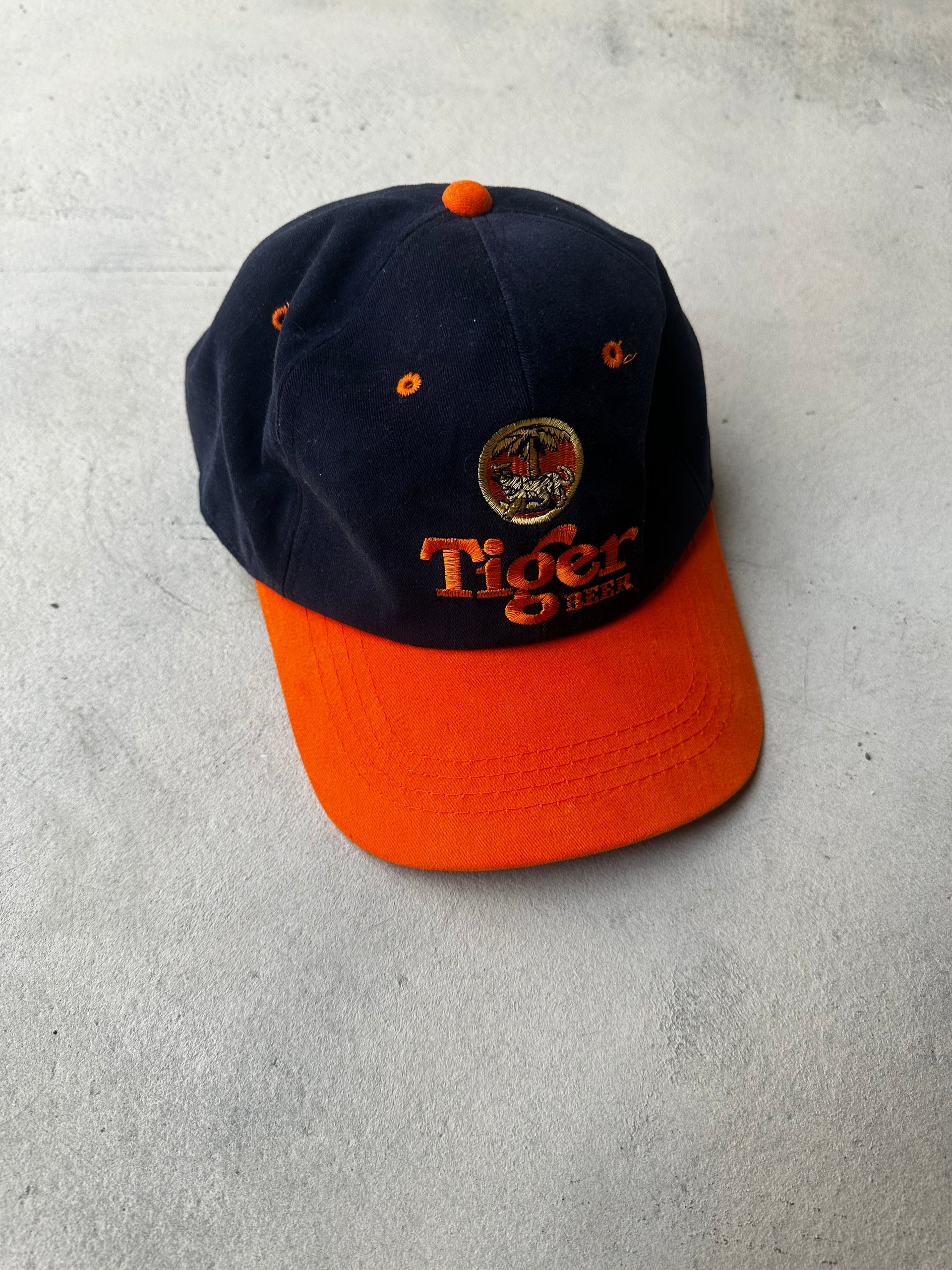 Vintage Tiger Beer cap with navy and orange two-tone design.
