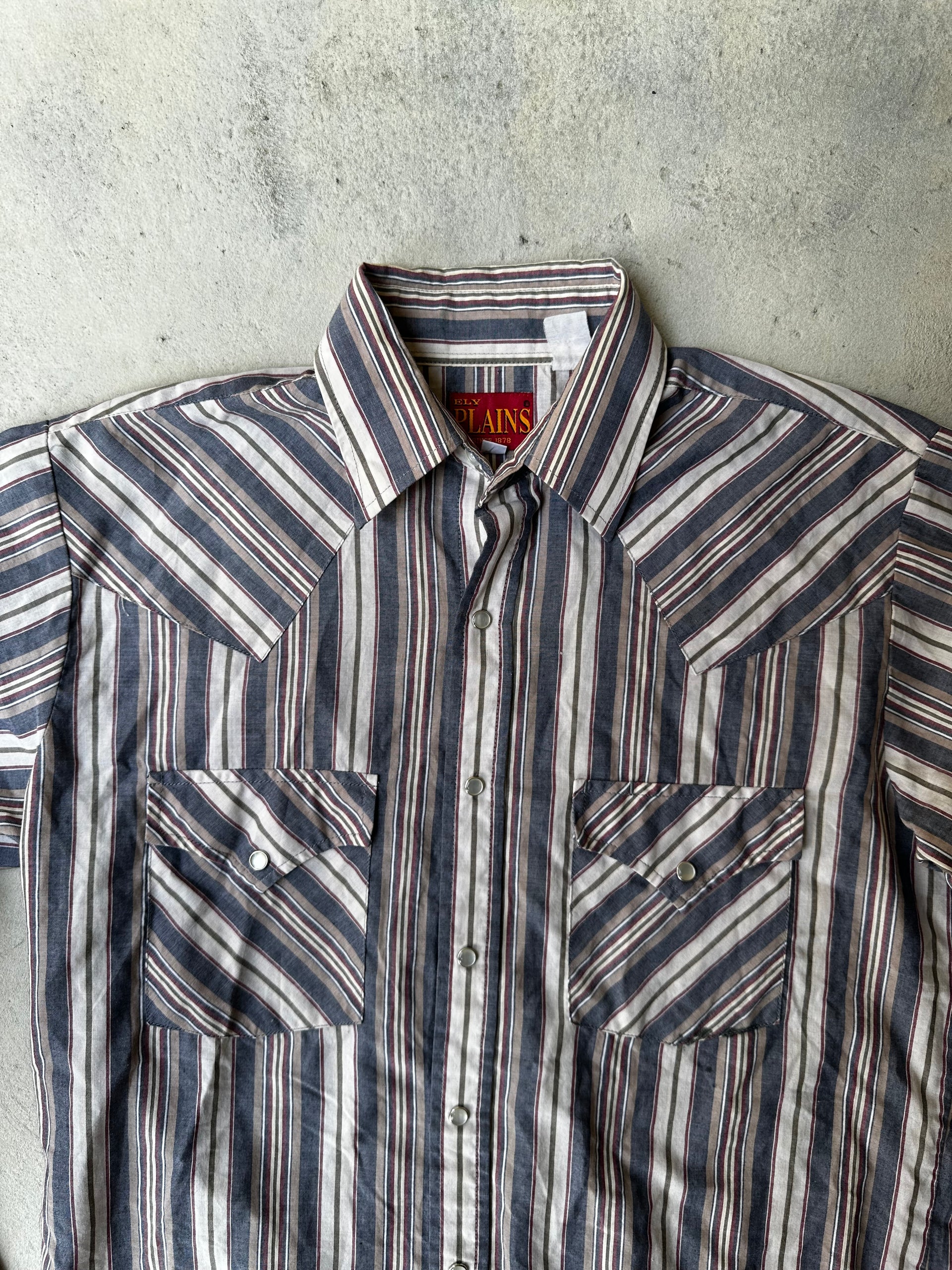 Close-up of striped western shirt featuring pearl snap buttons and contrast stitching