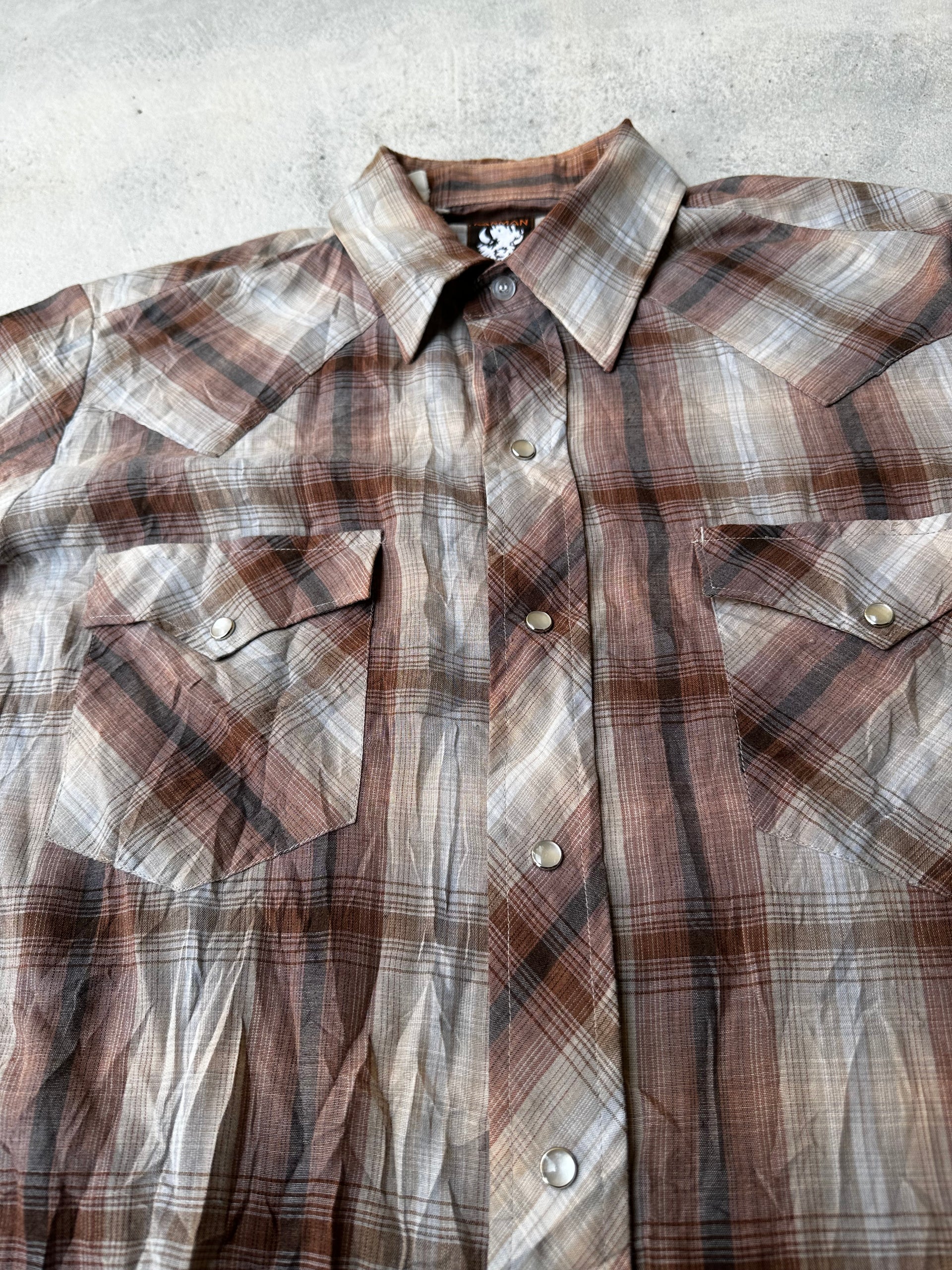 "Laid-flat pearl snap western shirt, showcasing worn-in fabric and faded tones."
